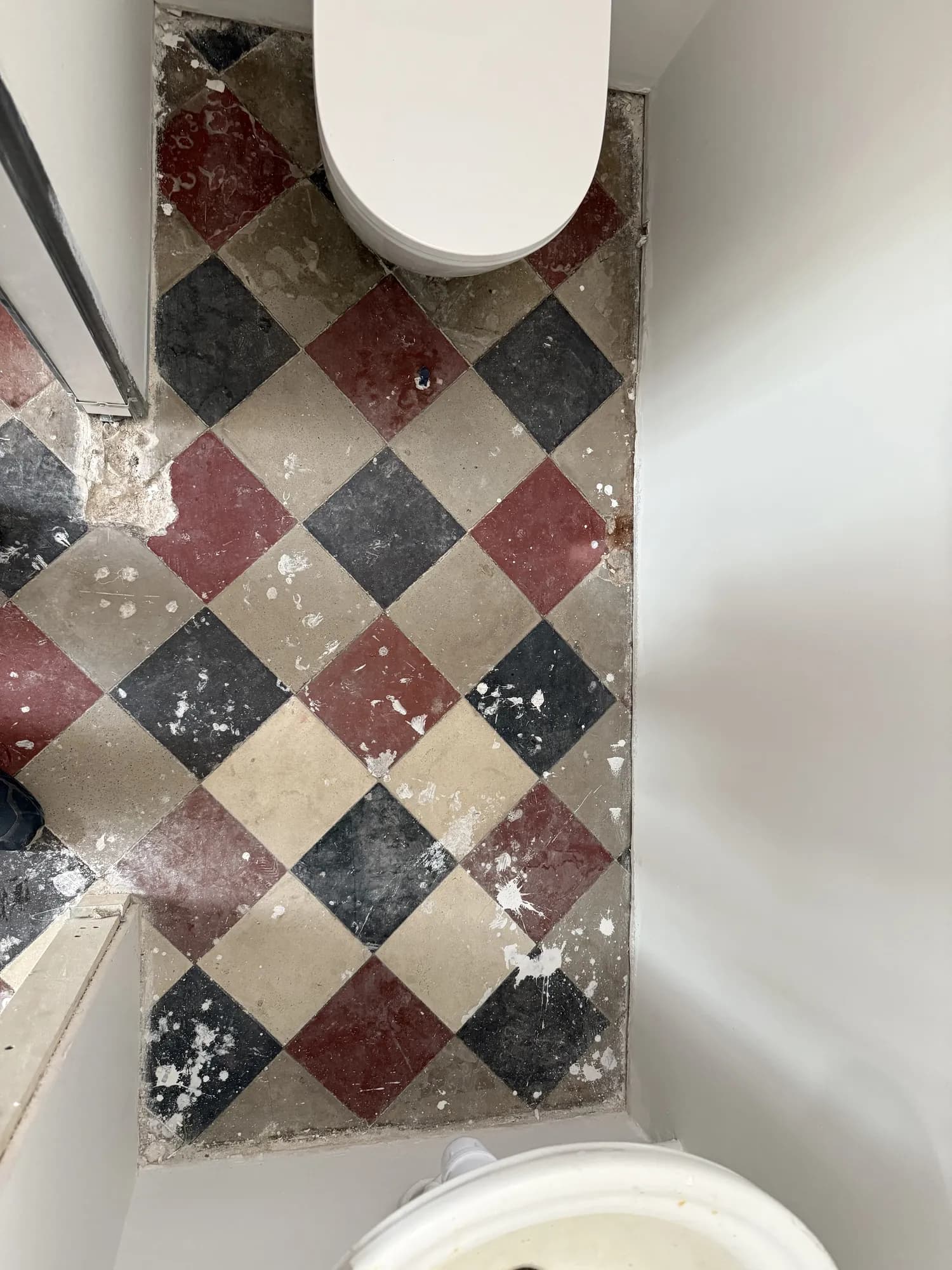 Sol de WC en damier taché de peinture et de plâtre avant nettoyage de fin de chantier