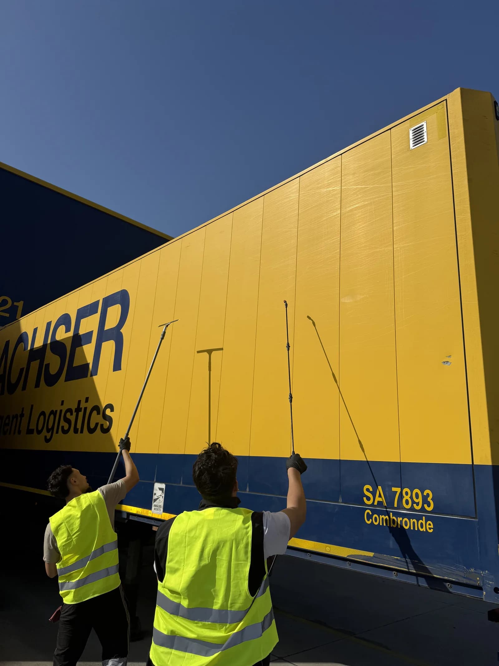 Techniciens JB Service en gilet haute visibilite nettoyant la remorque d'un camion DACHSER pour la gestion de flotte logistique a Lyon