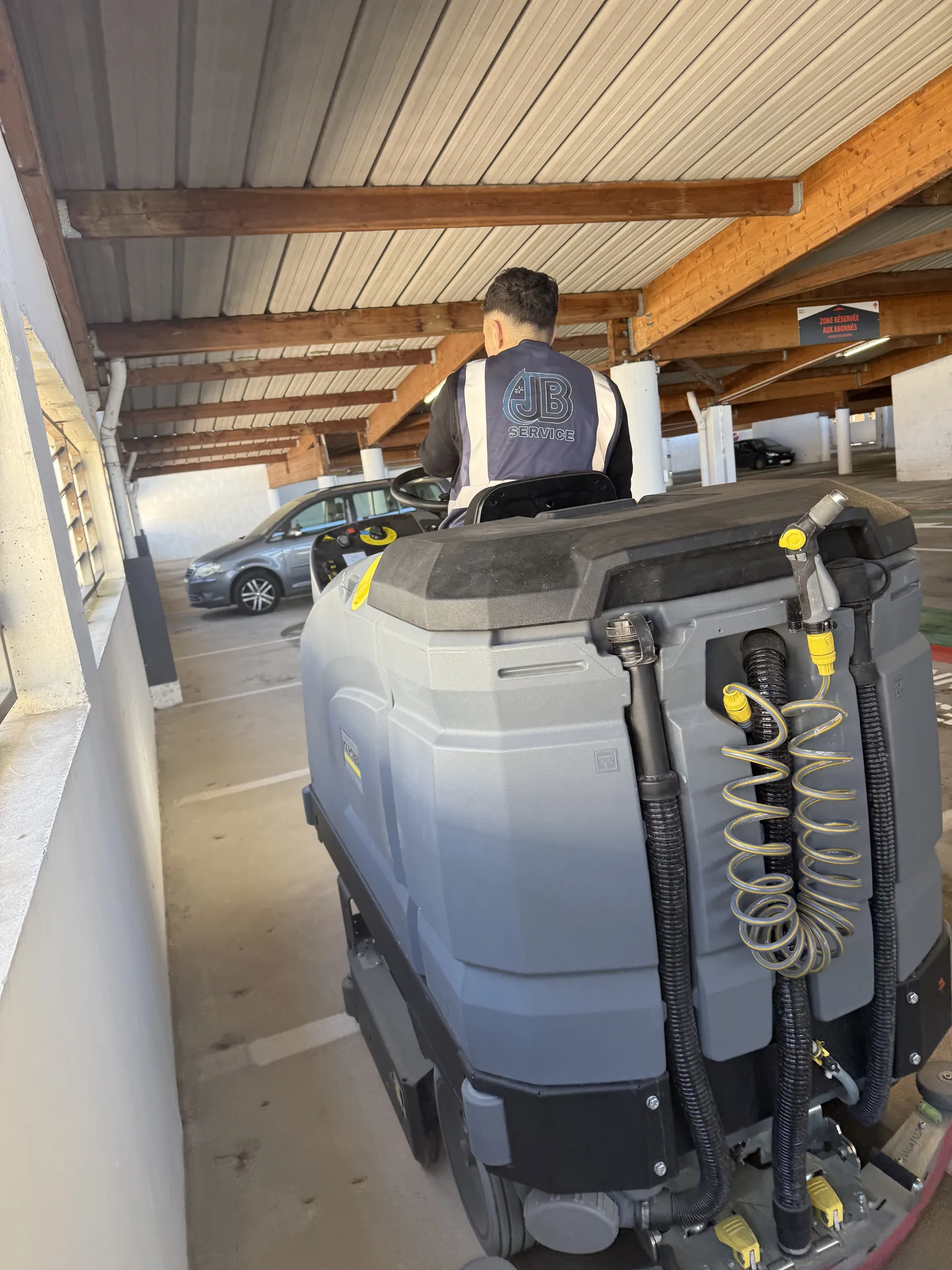 Autolaveuse autoportee JB Service nettoie un parking exterieur couvert a charpente bois a Lyon