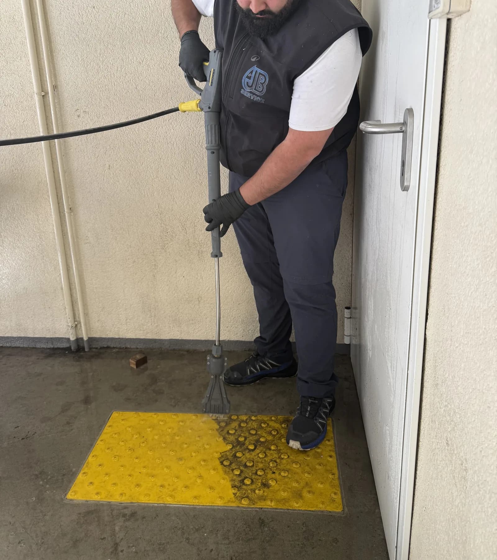 Decrassage haute pression d'une bande podotactile jaune dans un parking a Lyon par JB Service